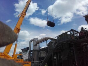 Kran hebt einen Elektromotor in einer Industrieumgebung